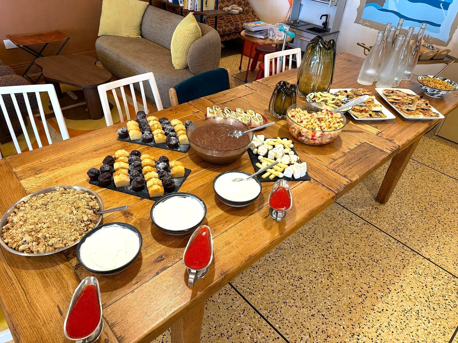 Buffet salé et sucré dressé sur une grande table en bois : cakes, fondants, fromages, salades et pizzas