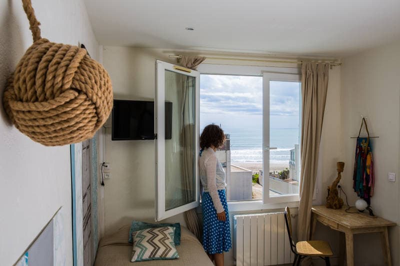 Cliente à la fenêtre d'une chambre avec vue sur la mer