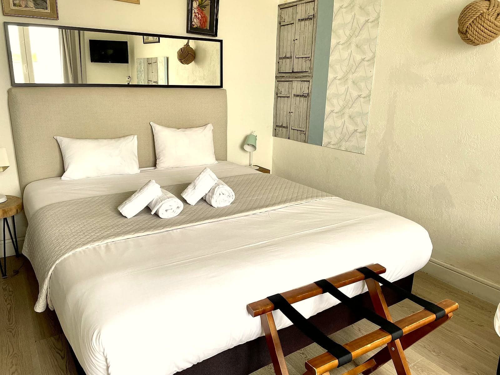 Chambre triple claire avec grand lit, serviettes roulées et porte-bagages
