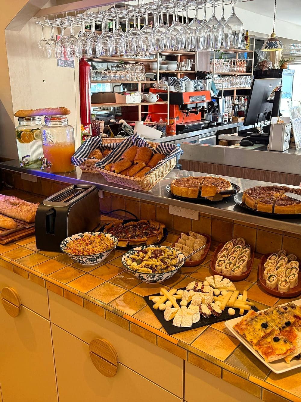 Pause gourmande dressée sur le comptoir du bar : viennoiseries, tartes, jus et café