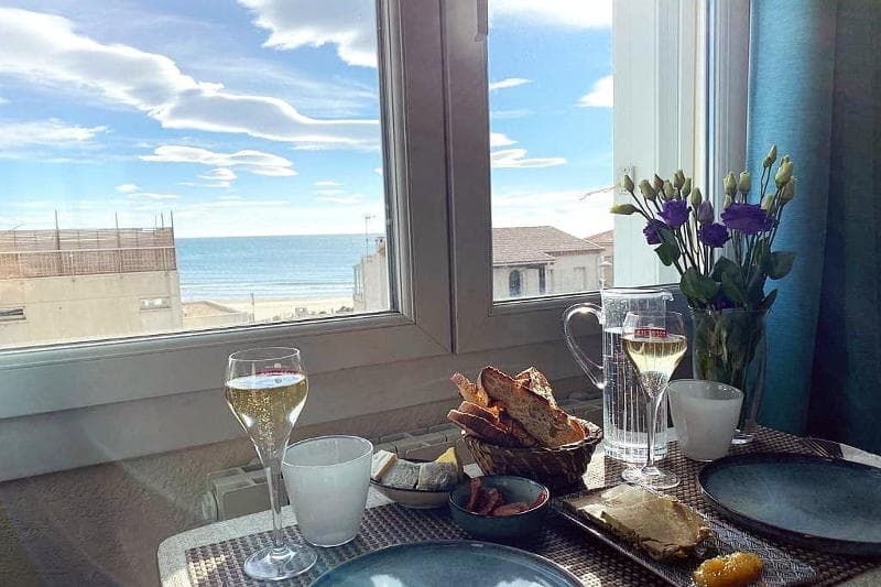 Table de travail devant une fenêtre ouverte sur la mer