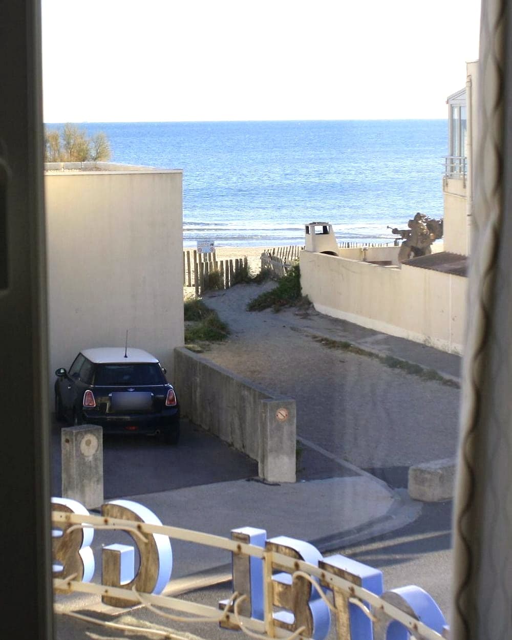 La mer vue depuis une fenêtre de l'hôtel, au bout de la rue, derrière l'enseigne du Gédéon